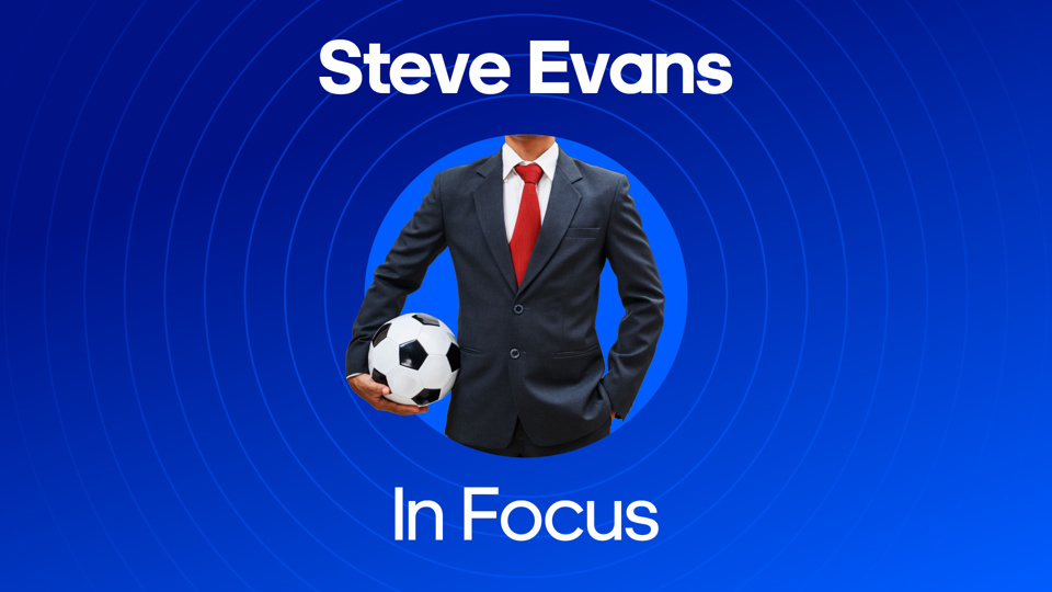 image of man in suit and tie holding football next to text of: Steve Evans In focus
